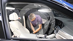 A car wash worker applies detergent to a car seat. Car cleaning concept