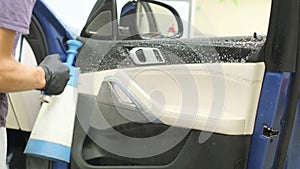 A car wash worker applies detergent to a car seat. Car cleaning concept