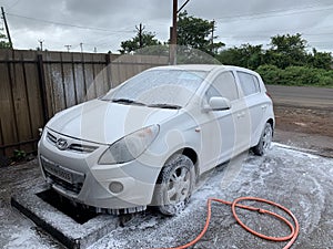Car washing concept. Car in foam. Car getting a wash with soap, car washing.