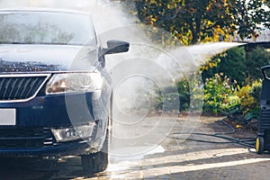 Car washing with pressure washer on backyard