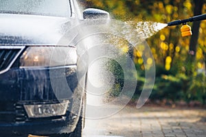 Car washing with pressure washer on backyard