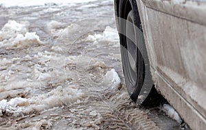 Car wheel against the background of melting dirty snow