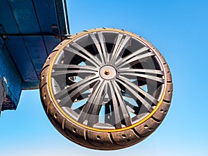 A car wheel attached to the roof of a building against the blue sky.