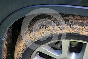 Car wheel caked in red dirt closeup