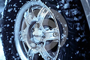 a car wheel closeup on the background of a winter snow covered road, concept of traffic safety on a slippery road
