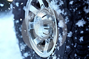 a car wheel closeup on the background of a winter snow covered road, concept of traffic safety on a slippery road