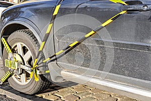 Car wheel is locked due illegal parking violation. Police equipment for blocking the car wheel of a parking photo