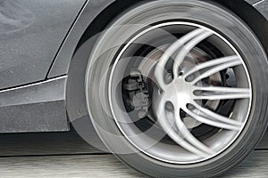 Car wheel in motion on the road, brake caliper