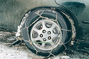 Car wheel with snow chains. The fenders of the car are forgotten by the muddy snow. The concept of safety on snowy roads