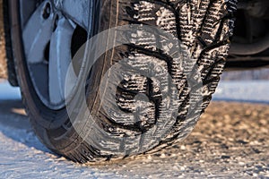 Car wheel with winter studded tread on snowy road