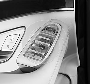 Car white leather interior details of door handle with windows controls and adjustments. Car window controls of modern car. Car de photo