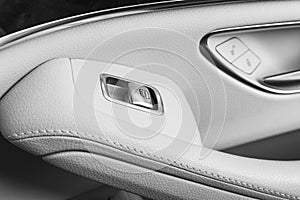 Car white leather interior details of door handle with windows controls and adjustments. Car window controls of modern car. Car de photo