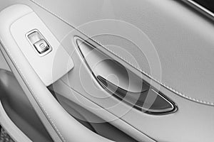 Car white leather interior details of door handle with windows controls and adjustments. Car window controls of modern car. Car de photo