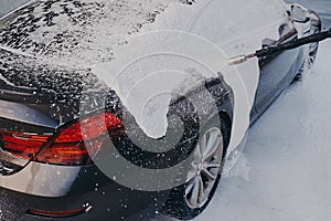 Car in white soap suds during professional auto cleaning outdoor