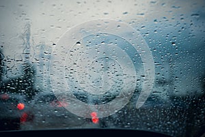 Car window with rain drops on glass or the windshield,Blurred traffic on rainy day in the city