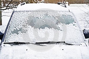 Car window under a layer of snow. Snow cover texture on smooth glass car