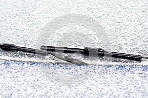 Car windows and wipers covered with snow in winter