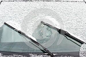 Car windows and wipers covered with snow in winter