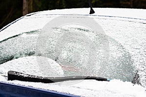 Car windows and wipers covered with snow in winter