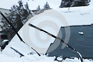 Car with windscreen wipers covered with snow outdoors on winter day