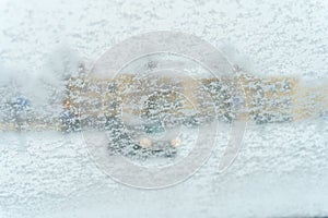 Car windshield covered in snow with out of focus background