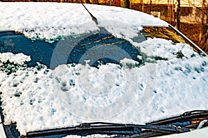 Car windshield partially covered with snow