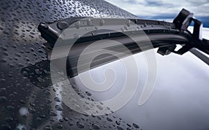 Car windshield with rain drops and frameless wiper blade closeup