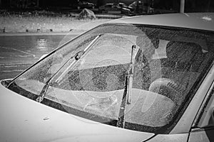 Car windshield wipers in rainy season, black and white photo with vignetting, front and rear background blurred with bokeh effect