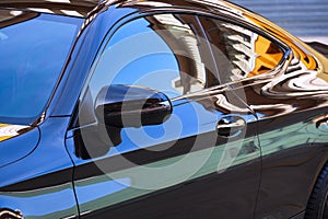 Car wing mirror with colorful reflection on surface of modern automobile black car