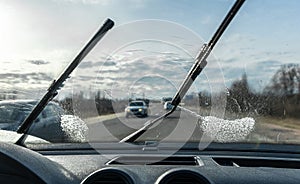 Car wipers clean windshields when driving in sunny weather.