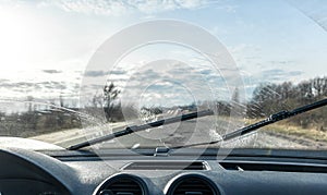 Car wipers clean windshields when driving in sunny weather.