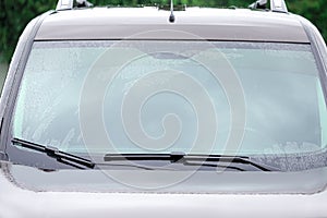 Car wipers cleaning water drops from windshield glass, closeup