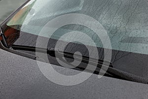 Car wipers cleaning water drops from windshield glass, closeup