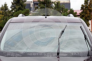 Car wipers cleaning water drops from windshield glass outdoors, closeup