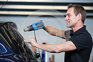 Car wrapper using heat gun and squegee for tinting window