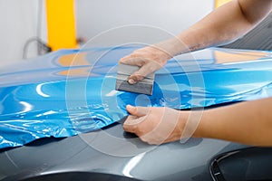 Car wrapping, mechanic with squeegee installs film