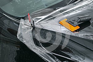 Car wrapping specialist putting vinyl foil or film on car. Protective film on the car. Applying a protective film to the car with