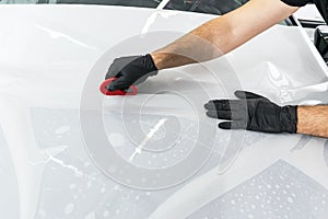 Car wrapping specialist putting vinyl foil or film on car. Protective film on the car. Applying a protective film to the car with