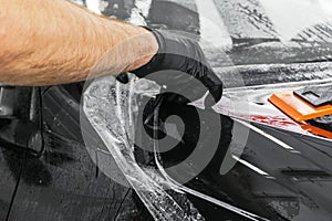 Car wrapping specialist putting vinyl foil or film on car. Protective film on the car. Applying a protective film to the car with