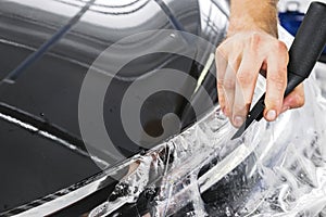 Car wrapping specialist putting vinyl foil or film on car. Protective film on the car. Applying a protective film to the car with