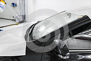 Car wrapping specialist putting vinyl foil or film on car. Protective film on the car. Applying a protective film to the car with