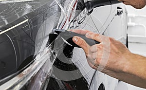 Car wrapping specialist putting vinyl foil or film on car. Protective film on the car. Applying a protective film to the car with