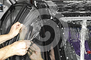 Car wrapping specialist putting vinyl foil or film on car. Protective film on the car. Applying a protective film to the car with