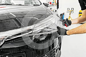 Car wrapping specialist putting vinyl foil or film on car. Protective film on the car. Applying a protective film to the car with