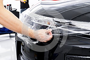 Car wrapping specialist putting vinyl foil or film on car. Protective film on the car. Applying a protective film to the car with