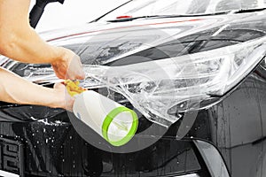 Car wrapping specialist putting vinyl foil or film on car. Protective film on the car. Applying a protective film to the car with