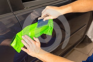 Car wrapping specialist wraps car door handle with adhesive foil or film photo