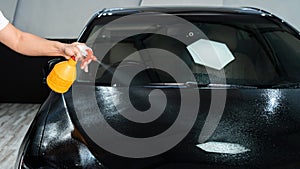 Car Wrapping Specialists spraying water before doing PPF installation process on a front headlight and hood.