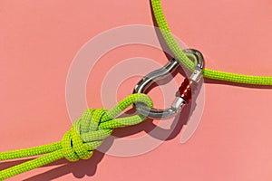 carabiner with a rope lies on a colored background. Equipment for climbing and mountaineering. reliable connection. Safety rope.