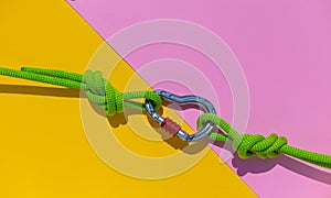 carabiner with a rope lies on a colored background. Equipment for climbing and mountaineering. reliable connection. Safety rope.